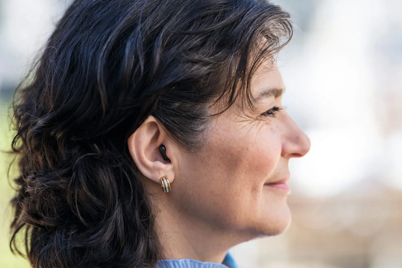 Mulher de perfil usando um aparelho auditivo pequeno dentro do ouvido